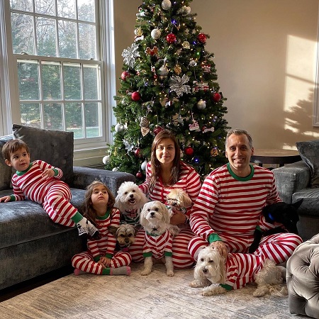 Joe Gatto with his wife Bessy Gatto, their two kids and five dogs in front of a Christmas tree.